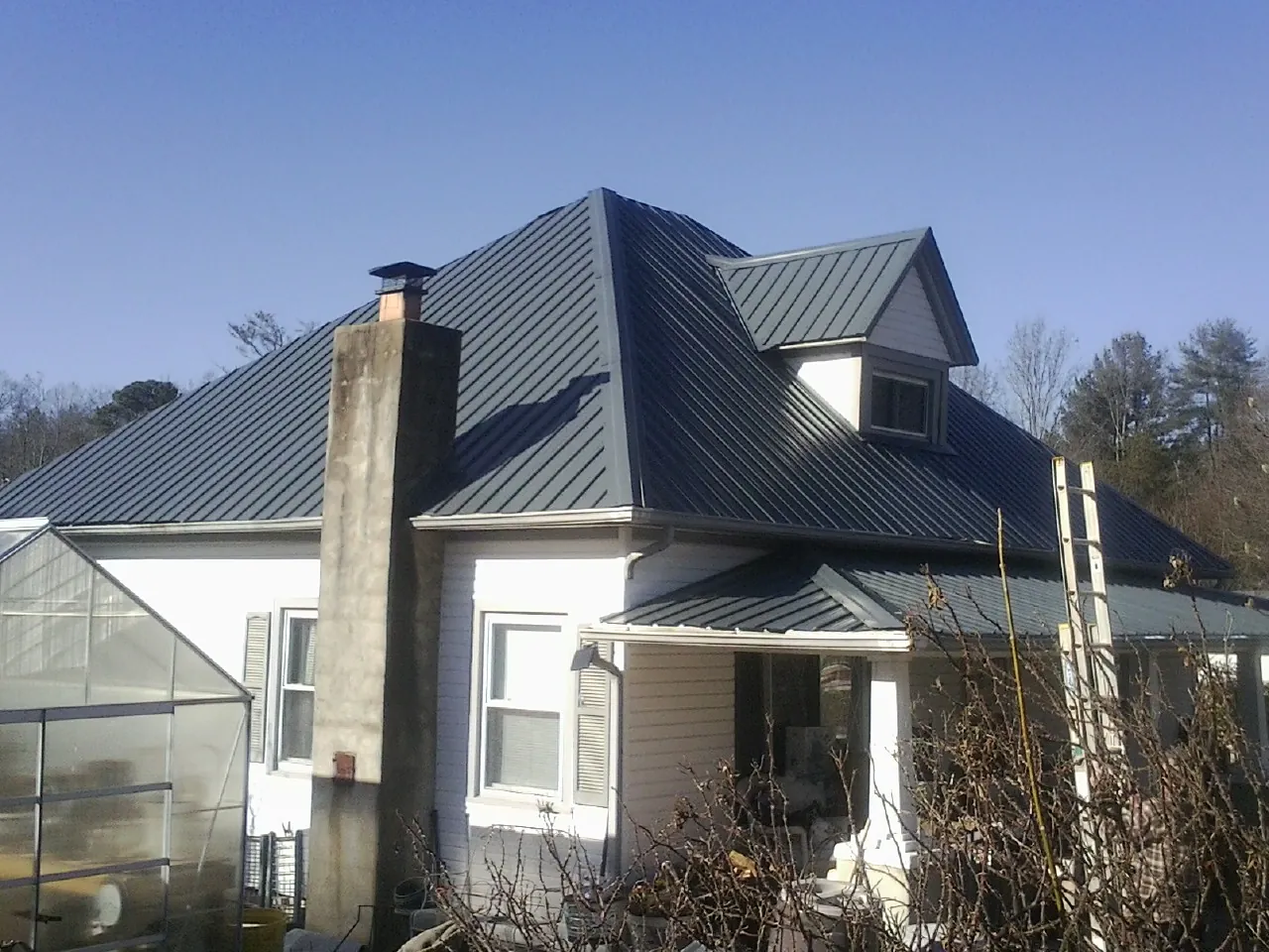 Dark blue standing seam metal roof on a white farmhouse with dormer — Slate & Tile Roof Repair by Roofing Brothers in Dundas