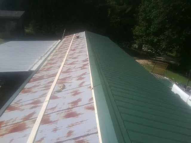 Old rusted panels beside newly installed green metal roofing — Wind Damage Roof Repair by Roofing Brothers in Dundas