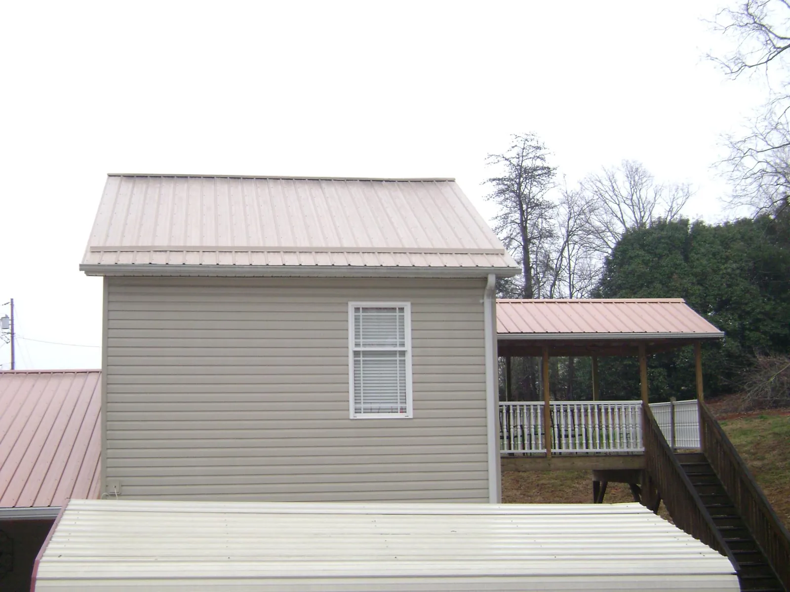 Tan metal roofs on a two story addition and attached porch, from a Roof Replacement job in Dundas